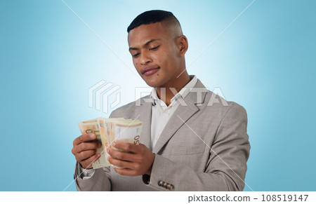 Business man, cash and money for financial investment, budget and trading, profit or counting his savings in studio. Young trader with decision or doubt for income, loan or salary on blue background Business man, cash and money for financial investment, budget and trading, profit or counting his savings in studio. Young trader with decision or doubt for income, loan or salary on blue background 108519147