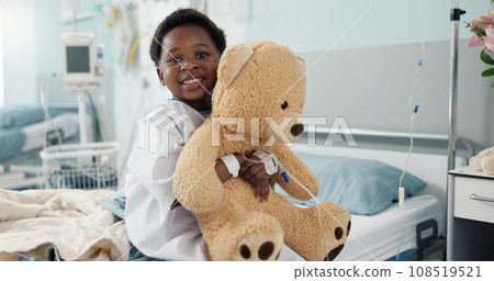 African boy child, hospital and teddy bear on bed with face, smile and rest for recovery for healthcare treatment. Patient kid, happy and portrait to relax, clinic and hug with toys after surgery 108519521