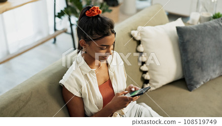 Woman, typing and scroll on smartphone in home for social network, update multimedia subscription or chat on sofa from above. Indian girl, phone and download mobile games, reading notification or app 108519749