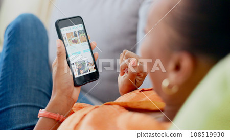 Hands, phone and food order with a black woman on a sofa to relax in the living room of her home. Mobile, screen or display with an online customer searching for a luxury product on a meal website 108519930