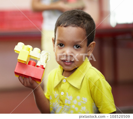 Boy, portrait and building blocks in classroom for development, scholarship and games at kindergarten. Happy student child, plastic toys and smile for education at academy, school or growth in class 108520509