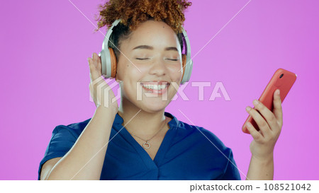 Headphones, music and woman with smartphone in studio listening to song, audio or radio. Happy, smile and face of person with mobile app for streaming subscription, relax and fun on purple background Headphones, music and woman with smartphone in studio listening to song, audio or radio. Happy, smile and face of person with mobile app for streaming subscription, relax and fun on purple background 108521042