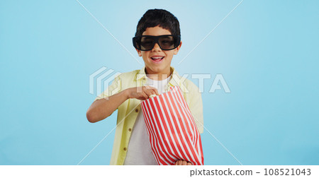 Popcorn, 3d or child in studio for a movie, watching tv or VR film on blue background with snack. Future technology, virtual reality experience or kid eating food for 3d cinema or metaverse show Popcorn, 3d or child in studio for a movie, watching tv or VR film on blue background with snack. Future technology, virtual reality experience or kid eating food for 3d cinema or metaverse show 108521043