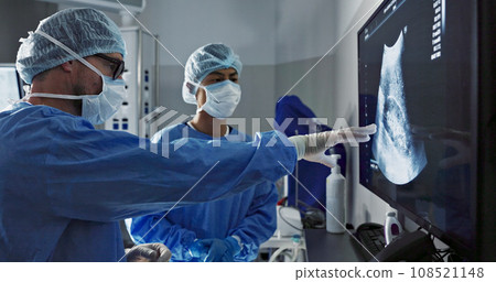 Surgery, x ray and a team of doctors in the hospital for an operation or procedure to remove a tumor. Healthcare, medical teamwork and a surgeon looking at a screen with a medicine professional 108521148