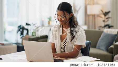 Laptop, remote work and woman typing for research in the living room of modern apartment. Smile, technology and young Indian female freelancer working on creative project with computer at home. 108521163