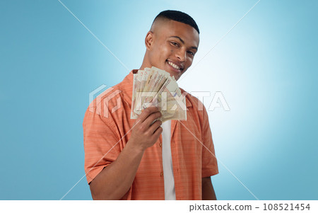 Happy man, winner and money fan with success, bonus or winning in competition, college loan or cashback in studio. Portrait of student with cash, savings and scholarship funding on a blue background Happy man, winner and money fan with success, bonus or winning in competition, college loan or cashback in studio. Portrait of student with cash, savings and scholarship funding on a blue background 108521454