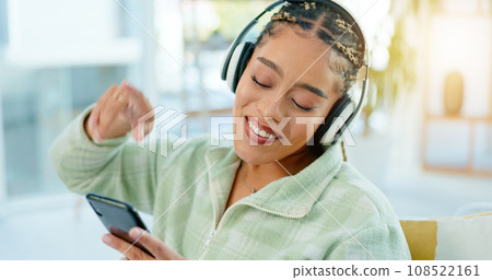 Phone, dance and happy woman on music headphones in home living room. Smartphone, radio and African person listening to podcast, audio and sound for freedom, celebration and streaming media online 108522161