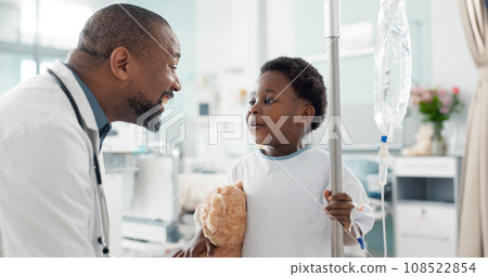Pediatrician, happy and doctor playing with child as care, support and kindness in healthcare in a hospital or clinic. Iv drip, teddy bear and African professional with medical compassion for kid Pediatrician, happy and doctor playing with child as care, support and kindness in healthcare in a hospital or clinic. Iv drip, teddy bear and African professional with medical compassion for kid 108522854