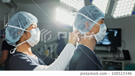 Surgery, hospital and doctors tie mask in operating room for medical service, preparation and operation. Healthcare team, safety scrubs and people with uniform for emergency, procedure and protection Surgery, hospital and doctors tie mask in operating room for medical service, preparation and operation. Healthcare team, safety scrubs and people with uniform for emergency, procedure and protection 108523346