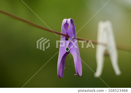 Clothespin. Closeup of neglected clothes pegs and housework, chores. Plastic clothespins hanging on washing cable or laundry line with bokeh and copy space outside. An abandoned hygiene routine. 108523466