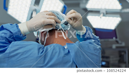 Surgery, prepare and doctor tie mask in operating room for medical service, protection and operation. Healthcare team, safety scrubs and person with uniform for emergency, procedure and wellness Surgery, prepare and doctor tie mask in operating room for medical service, protection and operation. Healthcare team, safety scrubs and person with uniform for emergency, procedure and wellness 108524224