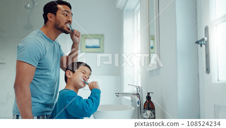 Father, child and brushing teeth in family home bathroom while learning or teaching dental hygiene. A man and kid with toothbrush and toothpaste for health, cleaning mouth and wellness at mirror Father, child and brushing teeth in family home bathroom while learning or teaching dental hygiene. A man and kid with toothbrush and toothpaste for health, cleaning mouth and wellness at mirror 108524234