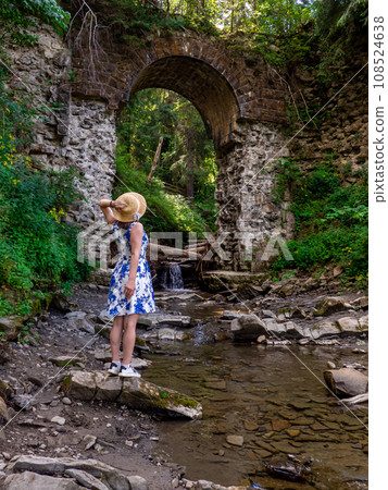 Old stone arched destroyed bridge over small river in a mountain forest Old stone arched destroyed bridge over small river in a mountain forest 108524638