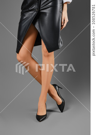 Closeup view of female legs in tights and leather skirt and shoes Closeup view of female legs in tights and leather skirt and shoes 108526781