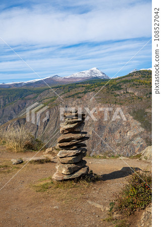 Pebbles stacked on arid landscape at Altai Mountains against cloudy sky, Russia 108527042