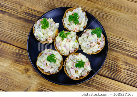 Traditional Russian festive salad Olivier in tartlets on wooden table 108527163