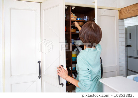 A woman who is worried about storage in the cupboard, rear view 108528823