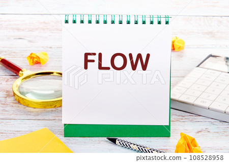 FLOW text on the white sheet of the notebook is next to a magnifying glass, calculator, pencil, stickers FLOW text on the white sheet of the notebook is next to a magnifying glass, calculator, pencil, stickers 108528958