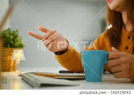 Cropped shot of young woman holding cup of coffee talking with friend over a video call 108529043