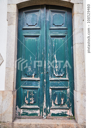 Old traditional wooden door with wrought iron door knockers on white facade in Portugal Old traditional wooden door with wrought iron door knockers on white facade in Portugal 108529460