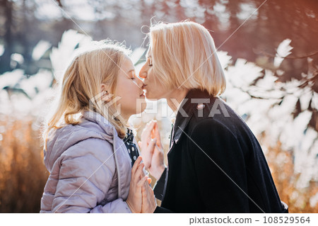 Mother and Teenage Daughter Relationship. Tips for Moms Raising Teenage Daughters to Fight Less and Connect More. Happy teen girl walking and playing with her mom in autumn park. Mother and Teenage Daughter Relationship. Tips for Moms Raising Teenage Daughters to Fight Less and Connect More. Happy teen girl walking and playing with her mom in autumn park. 108529564