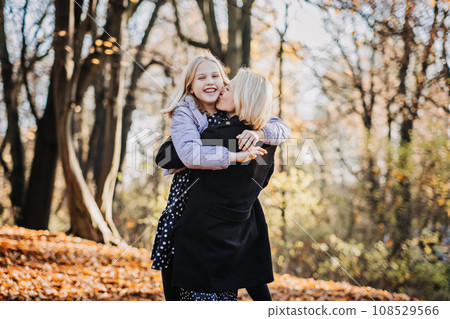 Mother and Teenage Daughter Relationship. Tips for Moms Raising Teenage Daughters to Fight Less and Connect More. Happy teen girl walking and playing with her mom in autumn park. 108529566