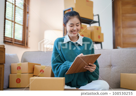 Starting small business entrepreneur of independent Asian female online seller packing products to send to customers and SME delivery concept. Starting small business entrepreneur of independent Asian female online seller packing products to send to customers and SME delivery concept. 108530255