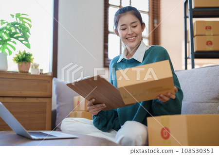 Starting small business entrepreneur of independent Asian female online seller packing products to send to customers and SME delivery concept. Starting small business entrepreneur of independent Asian female online seller packing products to send to customers and SME delivery concept. 108530351