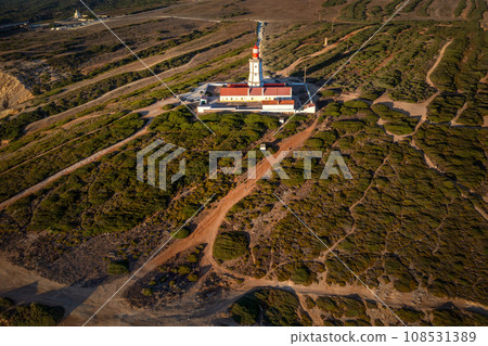 Sunset landscape with traditional lighthouse on Cabo Espichel or cape Espichel. Atlantic ocean coast, Sesimbra, Portugal. Seashores, high cliffs, Portuguese architecture, sundown, summer, drone shot Sunset landscape with traditional lighthouse on Cabo Espichel or cape Espichel. Atlantic ocean coast, Sesimbra, Portugal. Seashores, high cliffs, Portuguese architecture, sundown, summer, drone shot 108531389