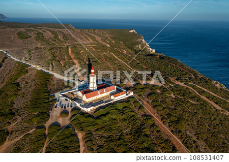 Beautiful sunset view of lighthouse on Cabo Espichel or cape Espichel. Atlantic ocean coast, Sesimbra, Portugal. Seashores, high cliffs, Portuguese architecture, sunset summer landscape, blue sky 108531407