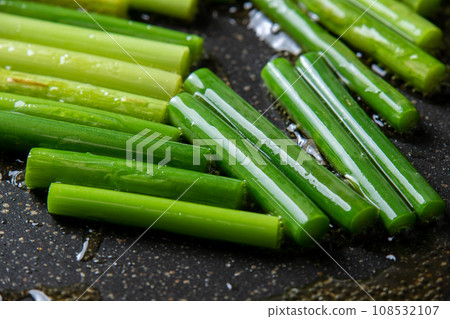 A cooking scene where garlic sprouts are fried in a frying pan. A cooking scene where garlic sprouts are fried in a frying pan. 108532107