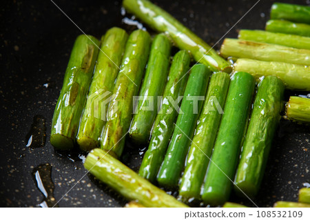 A cooking scene where garlic sprouts are fried in a frying pan. A cooking scene where garlic sprouts are fried in a frying pan. 108532109