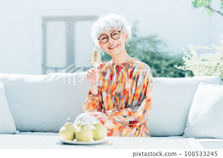 Senior woman drinking champagne in her garden 108533245