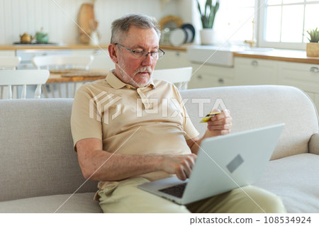 Senior man shopping online using laptop paying with credit card. Old grandfather buying on Internet enter credit card details. Online shopping delivery service. Older generation modern tech usage 108534924