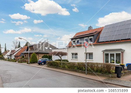 City street of single-family modern houses Germany against blue sky. German suburban small town residential area with row eco sustainable life building neighborhood suburb. Urban car parking driveway 108535899