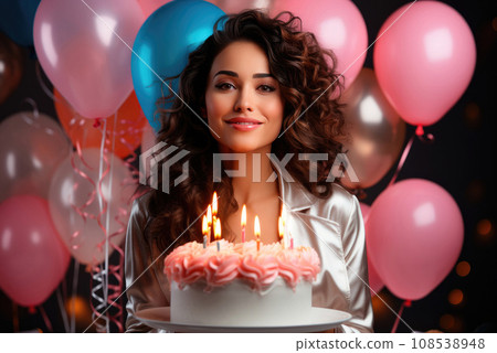 Young birthday woman holding a cake with candles in hands on the background of balloons 108538948