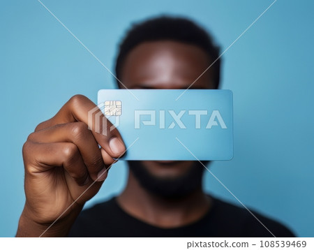 Male hand holding a blue bank card in front of his face on a blue background AI Male hand holding a blue bank card in front of his face on a blue background AI 108539469