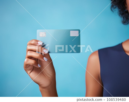 Female hand holding a blue bank card on a blue background AI 108539480