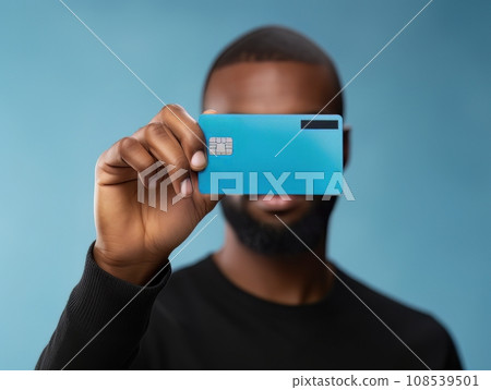 Male hand holding a blue bank card in front of his face on a blue background AI Male hand holding a blue bank card in front of his face on a blue background AI 108539501