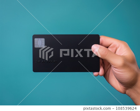 Male hand holding a black bank card on a blue background AI 108539624