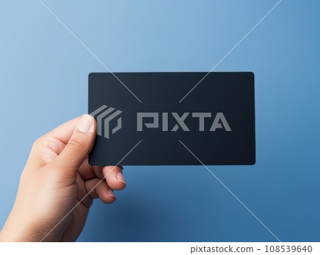 Male hand holding a black bank card on a blue background AI 108539640