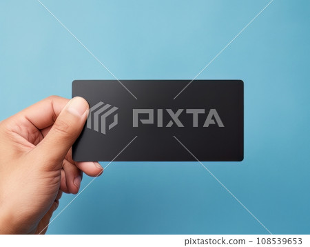 Male hand holding a black bank card on a blue background AI 108539653