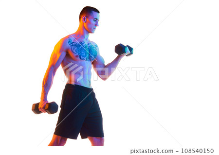 Shirtless young man with strong, fit, relief body training with dumbbells against white studio background in neon light Shirtless young man with strong, fit, relief body training with dumbbells against white studio background in neon light 108540150