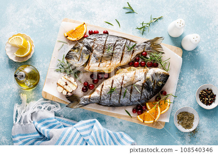 Dorado fish grilled with oranges, cranberries and rosemary, Mediterranean food. Christmas festive healthy dinner, top view 108540346