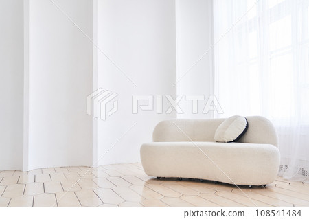 A soft empty white sofa stands on a white background curved by waves, a comfortable fabric sofa stands alone against a white wall, with space to copy. High quality photo 108541484