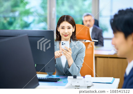 A young business woman looking at a smartphone in the office A young business woman looking at a smartphone in the office 108541522
