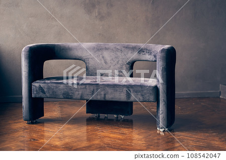 An elegant dark-colored sofa on a dark wall. One object on a dark background with space to copy. High quality photo 108542047