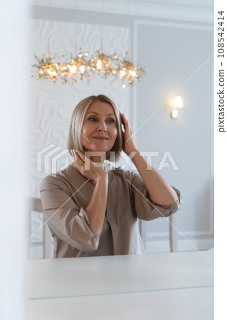 Senior woman sitting in front of mirror at home 108542414