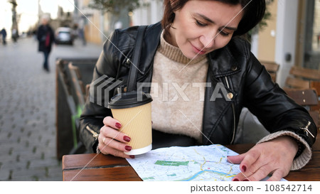 Stylish Female Tourist Checks City Sightseeing Route On Map While Sipping Coffee In Street Cafe Stylish Female Tourist Checks City Sightseeing Route On Map While Sipping Coffee In Street Cafe 108542714