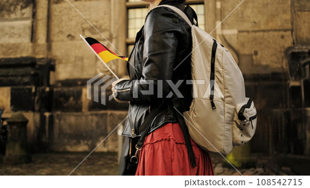 Attractive Female Tourist With Germany Flag Walks In Historical Center Of Dresden Carrying Backpack 108542715